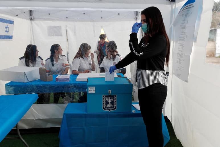 Una trabajadora israelí realiza una demostración del funcionamiento de una cabina de voto. (EFE)