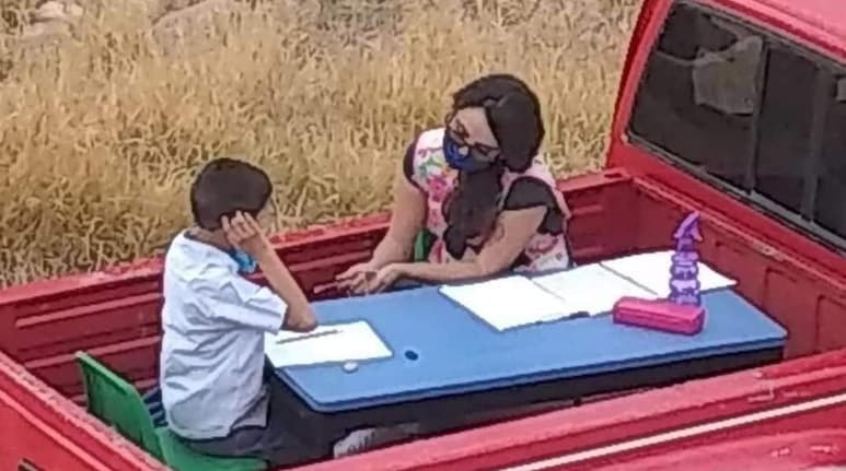 La mujer colocó una mesita en la parte trasera de su camioneta, donde enseña a sus alumnos a los que visita casa por casa (CAPTURA)