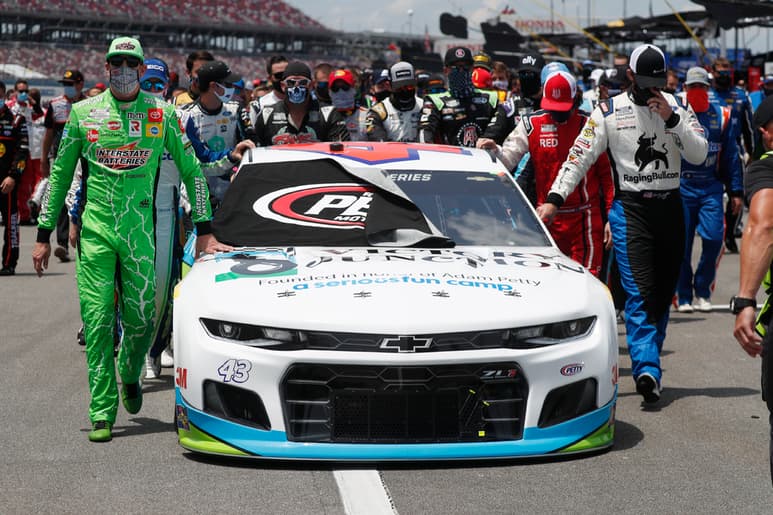 Pilotos y miembros de los diferentes equipos escoltaron el auto de Bubba Wallace previo a la carrera de ayer. (AP)