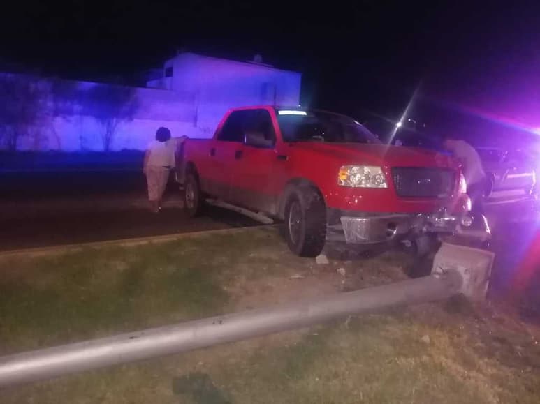 La camioneta Ford Lobo de color rojo impactó el poste de metal y arrancó la base de concreto que lo sostenía. (EL SIGLO DE TORREÓN)