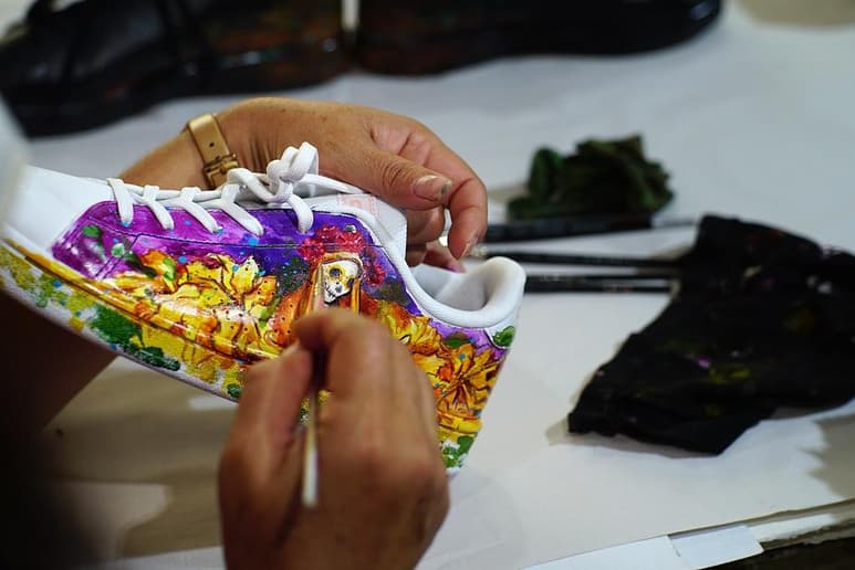 Durante el breve lapso que toma el pincel para llegar de la paleta de colores al nuevo lienzo, Arellano va creando una de las imágenes de su nueva colección 'Día de Muertos' en zapatillas deportivas. (Especial)