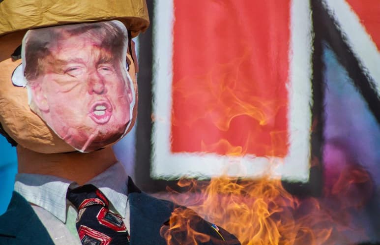 Unos 50 migrantes mexicanos y centroamericanos se reunieron a unos metros del muro fronterizo que divide a Estados Unidos y México, en donde protestaron contra la violencia policial con la quema de dos piñatas con la figuras de Donald Trump. (ARCHIVO)