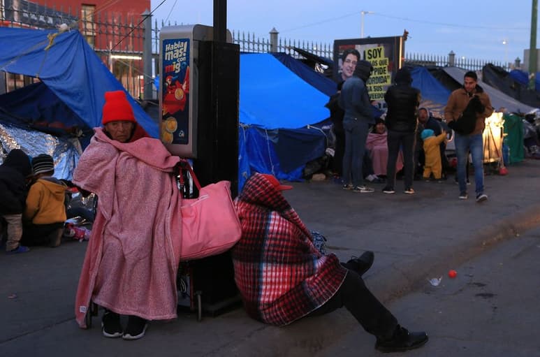 Migrantes se protegen del frío fuera de un albergue en Chihuahua.