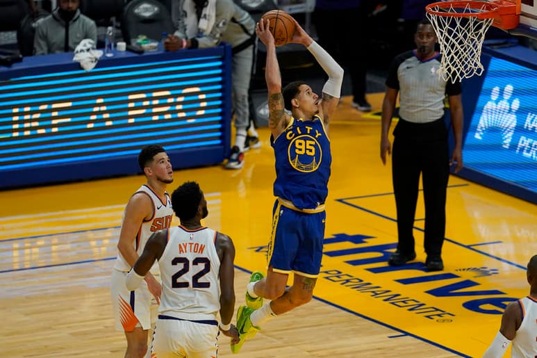 El alero de los Warriors de Golden State Juan Toscano-Anderson clava el balón frente a la mirada de Deandre Ayton y Devin Booker, de los Suns de Phoenix, durante la primera mitad del juego del martes 11 de mayo de 2021, en San Francisco. (AP Foto/Jeff Chiu)