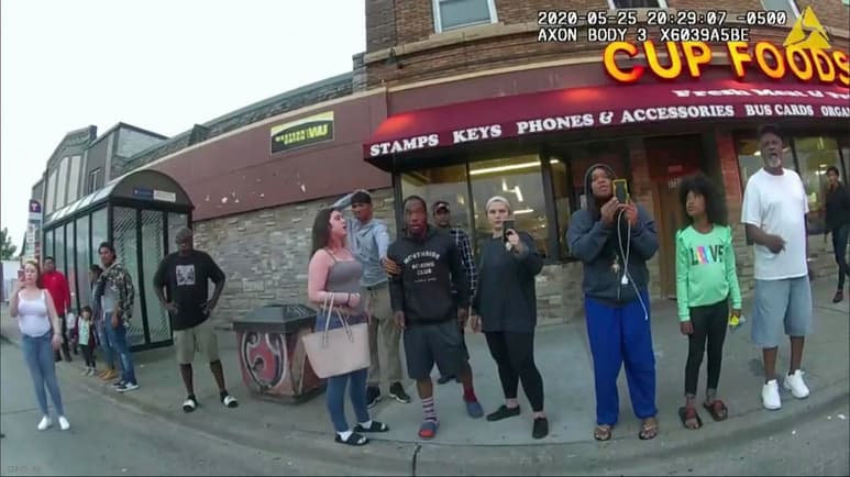 En esta fotografía de archivo del 25 de mayo de 2020 de una cámara portátil de policías, peatones, incluyendo a Darnella Frazier, tercera de derecha a izquierda filmando, mientras el ex policía de Minneapolis Derek Chauvin fue grabado presionando su rodilla sobre la nuca de George Floyd por varios minutos en Minneapolis. Frazier, quien grabó la muerte de Floyd, recibió una mención especial de los Premios Pulitzer el viernes 11 de junio de 2021 por grabar valientemente el video (Minneapolis Police Department via AP, File)