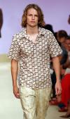 Una camisa verde y un pantalón naranja son mostrados por este modelo en el desfile porimevera-verano  2004 de Trussardi.