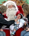 Santa Claus hacen sentir su presencia alrededor del mundo, aquí un bebe llora en sus brazos en Hyde Park  de Londres.
