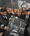 La canciller alemana Angela Merkel y los ex presidentes soviético Mijail Gorbachov y polaco Lech Walesa, sostienen una fotografía de personas cruzando la frontera luego de la caída del Muro de Berlín, al inicio de la conmemoración del suceso.