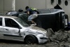 Un joven saquea un carro destruido por un terremoto.