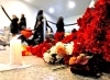 Pasajeros caminan junto a flores y velas encendidas en el lugar de la explosión en el aeropuerto Domodedovo.