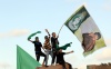 Seguidores del líder libio Muamar el Gadafi sostienen banderas nacionales y pancartas con su imagen.