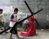 Un penitente filipinos carga con una cruz de madera por las calles de San Pedro Cutud.