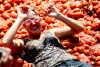 Una mujer en un suelo cubierto de tomate mientras celebra La Fiesta de la Tomatina o el Primer Tomate en Braga, Portugal.