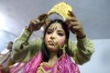 Una niña vestida de la diosa Radha se coloca los zaparos tras pagar sus respetos con motivo del Festival de Janamashtmi.