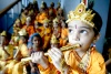 Un niño vestido del dios Lord Krishna toca la dlauta junto a sus compañeros del colegio con motivo del Festival de Janmashtami.