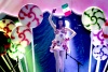 Del suelo se elevó la artista con una bandera de México en la mano, quien portaba un vestido blanco con paletas de caramelo que giraban como reguiletes y comenzó con una sonrisa en los labios y cantó el tema 'Teenage dream'.
