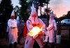 Un miembro de la orden de los Caballeros de la Brigada Rebelde del Ku Klux Klan (KKK) enciende una antorcha durante la ceremonia
