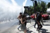 Manifestantes corren para resguardarse de los gases lacrimógenos.