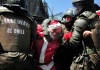 Carabineros de la policía uniformada de Chile detienen al manifestante vestido de Papá Noel.