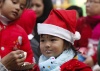Una niña vestida de Santa Claus come un pastel después de su primer festival navideño.