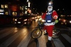Santa Claus espera la luz verde del semáforo para continuar con sus compras navideñas, en calles de la ciudad de México.