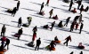 Niños juegan en un tobogan de nieve artificial en el estadio olímpico.