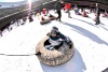 Niños juegan en un tobogan de nieve artificial en el estadio olímpico.