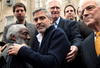 El actor George Clooney (L) habla como su padre, el periodista Nick Clooney (R) escucha durante una protesta frente a la embajada Sudanesa.