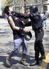 Un mosso detiene a un joven manifestante.