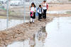 Niños de la colonia Villas Universidad caminan entre charcos en el primer día de escuela. La lluvia sorprendió a La Laguna en el regreso a clases, provocando caos vial aunque sin accidentes.