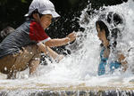 Los niños juegan en la fuente de agua en el parque de Asuka en Tokio.