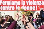 Mujeres posan con flores bajo una pancarta que reza "detengamos la violencia contra la mujer" en Florencia, Italia.