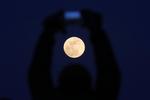 Un hombre usa la cámara de su móvil para hacer una foto de la llamada superluna azul en Pekín, Chinan.
