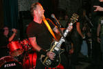 James Hetfield, vocalista de Metallica, cantando enérgicamente mientras toca una Les Paul diseñada a su gusto.