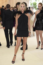 La supermodelo británica Kate Moss con un vestido corto negro y plumaje sobre sus hombros.