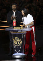 Chadwick Boseman, centro izquierda, besa a la presentadora Tiffany Haddish, centroderecha, mientras acepta el premio a la mejor película por Black Panther.