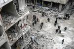 Fotografía publicada como parte de la historia 'Syria, No Exit' que muestra a personas que inspeccionan el 22 de febrero de 2018 los escombros de los edificios dañados después de varios ataques aéreos el día anterior, en Douma, la localidad de Guta (Siria).