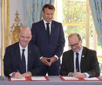 El presidente francés, Emmanuel Macron, sonríe este lunes durante la firma de un acuerdo entre el presidente de la FIFA, Gianni Infantino, y el director de la Agencia Francesa de Cooperación, Remy Rioux.