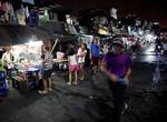 Varias personas caminan por un mercado en una zona deprimida de Manila.