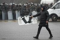 A demonstrator carries a police shield in front of police line during a protest in Almaty, Kazakhstan, Wednesday, Jan. 5, 2022. Demonstrators protesting rising fuel prices broke into the mayor's office in Kazakhstan's largest city Wednesday and flames were seen coming from inside, according to local news reports. Many of the demonstrators who converged on the building in Almaty carried clubs and shields, the Kazakh news site Zakon said. (AP Photo/Vladimir Tretyakov)