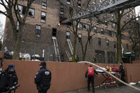Firefighters and NYPD officers work outside an apartment building after a fire in the Bronx, Sunday, Jan. 9, 2022, in New York. (AP Photo/Yuki Iwamura)