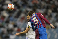 Real Madrid's Karim Benzema heads the ball in front of Barcelona's Gerard Pique during the Spanish Super Cup semi final soccer match between Barcelona and Real Madrid at King Fahd stadium in Riyadh, Saudi Arabia, Thursday, Jan. 13, 2022. (AP Photo/Hassan Ammar)