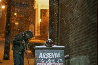 A person sweeps away snow on the sidewalk on 44th Street in Lawrenceville as snow falls during a winter storm that will impact the region on Sunday night, Jan. 16, 2022, in Lawrenceville a neighborhood in Pittsburgh, Pa. (Alexandra Wimley/Pittsburgh Post-Gazette via AP)