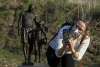 Nicole Such takes photos of a bronze sculpture honoring former Los Angeles Lakers NBA basketball player Kobe Bryant, his daughter Gianna Bryant, and the names of those who died, at the site of a 2020 helicopter crash in Calabasas, Calif, on Wednesday, Jan. 26, 2022. (AP Photo/Ringo H.W. Chiu)