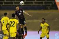 Mexico's Jose Andres Guardado heads the ball under the watch of Jamaica's Lamar Walker, right, during a qualifying soccer match for the FIFA World Cup Qatar 2022 in Kingston, Jamaica, Thursday, Jan. 27, 2022. (AP Photo/Ramon Espinosa)