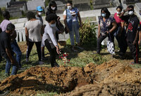 A daughter of 54-year-old woman Zilmar Batista, who died in the mudslides, sprinkles flower petals over her mother's casket at the Municipal cemetery in Petropolis, Brazil, Thursday, Feb. 17, 2022. Deadly floods and mudslides swept away homes and cars, but even as families buried their dead, it was unclear how many bodies remained trapped in the mud. (AP Photo/Silvia Izquierdo)