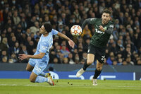 Manchester City's Ilkay Gundogan, left, is challenged by Sporting's Bruno Tabata during the Champions League round of 16 second leg soccer match between Manchester City and Sporting Lisbon at the City of Manchester Stadium in Manchester, England, Wednesday, March 9, 2022. (AP Photo/Dave Thompson)
