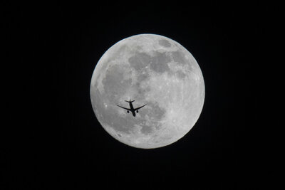 An aircraft flies past the full moon over Basra, Iraq, Sunday, May 15, 2022. (AP Photo/Nabil al-Jurani)