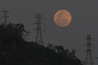 A full moon rises behind the high voltage towers of the El Avila in Caracas, Venezuela, Sunday, May 15, 2022. People in the Americas, Europe and Africa will see the total lunar eclipse during the night of May 15-16. (AP Photo/Matias Delacroix)