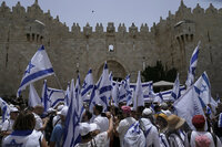 Israelis wave national flags in front of Damascus Gate outside Jerusalem's Old City to mark Jerusalem Day, an Israeli holiday celebrating the capture of the Old City during the 1967 Mideast war, Sunday, May 29, 2022. Israel claims all of Jerusalem as its capital. But Palestinians, who seek east Jerusalem as the capital of a future state, see the march as a provocation. Last year, the parade helped trigger an 11-day war between Israel and Gaza militants. (AP Photo/Mahmoud Illean)